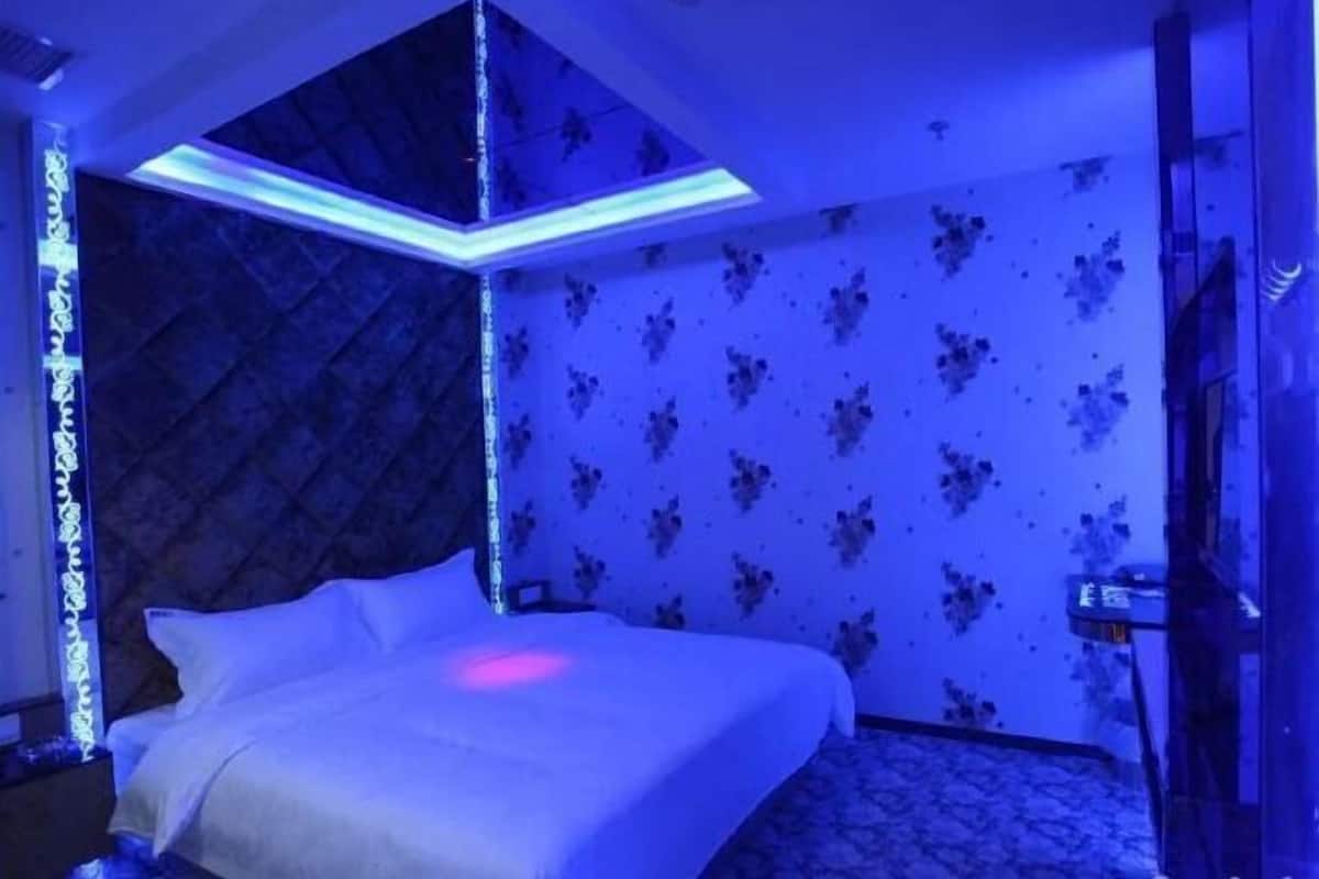 Een kamer met een bed, een plafondlamp en een bloemenprint op de muur.