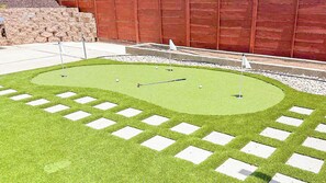 Un parcours de mini-golf doté d’un tapis vert pour les putts, de départs blancs et d’un fond en bois rouge.