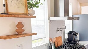 Une cuisine moderne dotée d’un îlot central, de meubles de couleur grise et d’une hotte de cuisson en acier inoxydable.