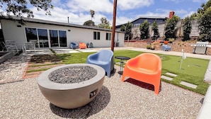 Un espace patio doté d’un foyer extérieur, de sièges de jardin et d’une pelouse bien entretenue.
