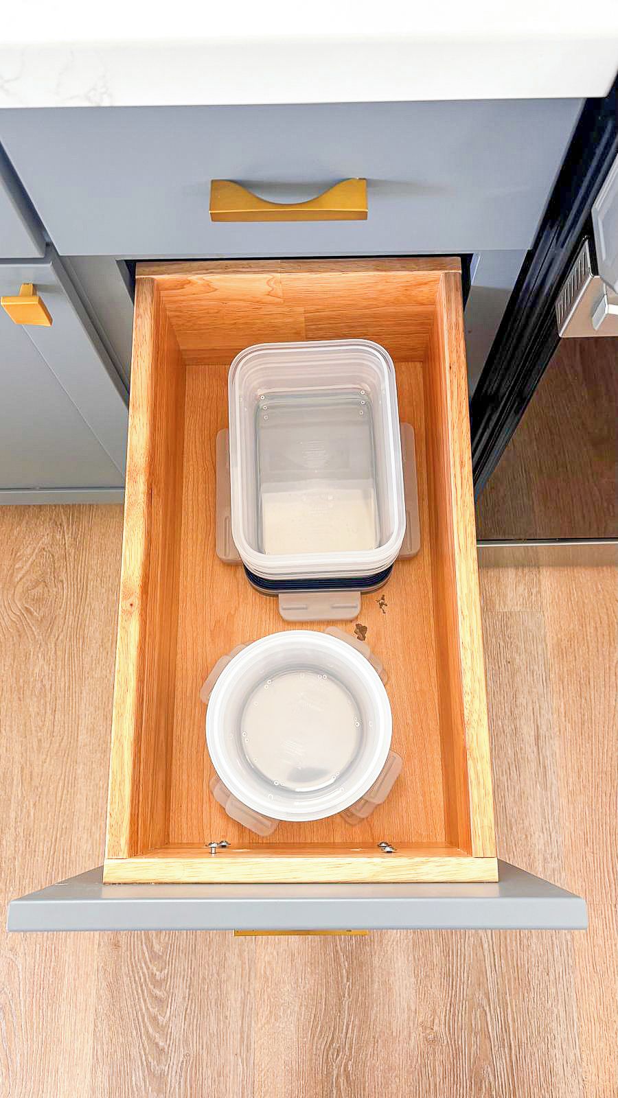 Een keukula met een houten binnenkant, met een witte bord en een transparante plastic bak.