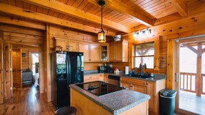 L’intérieur d’un chalet en bois comprend une cuisine équipée d’un réfrigérateur, d’une cuisinière et de tabourets de bar.