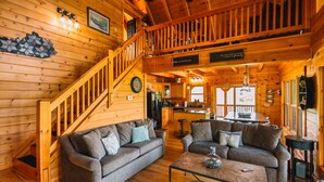 Un intérieur de chalet chaleureux avec un escalier en bois, un coin repas et une cuisine.