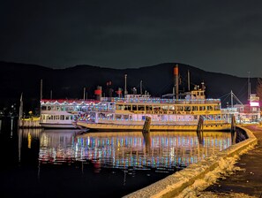 Et flodbåds skib ligger fortøjet ved en bro, med et bjergrigt landskab i baggrunden.