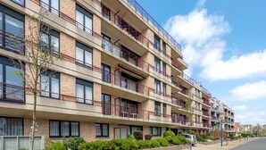 A multi-story residential building with balconies, windows, and a clear sky. - Cozy 2-bedroom Apartment Near Koksijde Beach (Koksijde)