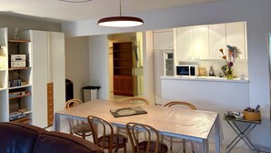 A compact living space with a dining area, kitchenette, and built-in storage. - Cozy 2-bedroom Apartment Near Koksijde Beach (Koksijde)