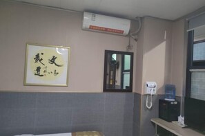 A hotel room with a bed, a framed calligraphy piece, a mirror, a phone, and a water dispenser. - Hanlin Business Hotel (Huaibei)