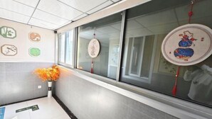 A corridor with a tiled floor, a vase with flowers, and decorative wall art.