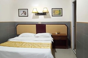 A hotel room with a bed, bedside table, lamp, and two framed pictures on the wall. - Hanlin Business Hotel (Huaibei)