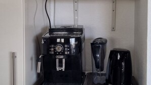 A compact kitchenette with a microwave, coffee maker, and blender on a countertop, and a dishwasher below.