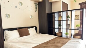 Un lit bien fait, agrémenté d’une touche de couleur marron, un mur orné de miroirs ronds et une petite plante, ainsi qu’une étagère avec des plantes en pot et des photos encadrées.