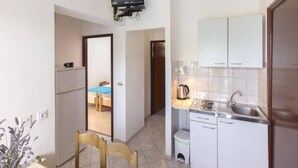 A compact kitchen with a built-in TV, a small dining area, and a visible bathroom. - Apartment in Brodarica by Sandy Beach (Sibenik)