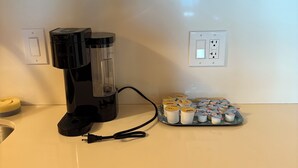 A kitchen with a coffee maker, a power outlet, and a tray of coffee pods.