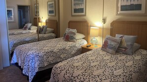 A hotel room with two beds, a large mirror, and framed artwork on the walls.