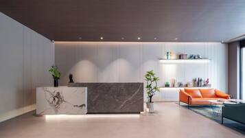 A modern reception area with a marble reception desk, a sofa, and a plant.