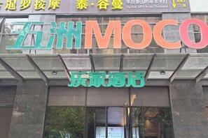 Un bâtiment sur lequel on peut lire l’inscription « MOCO » et un autre panneau avec des caractères chinois.