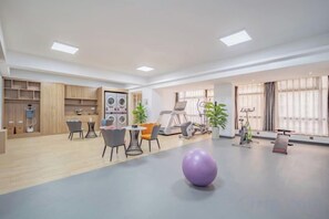 A spacious room with a dining area, exercise equipment, and a large window providing natural light. - Luck Hotel (Shijiazhuang Huai'an East Road) (Shijiazhuang)