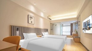 Une chambre d’hôtel avec deux lits, un bureau, une chaise, une table de chevet et une grande fenêtre.