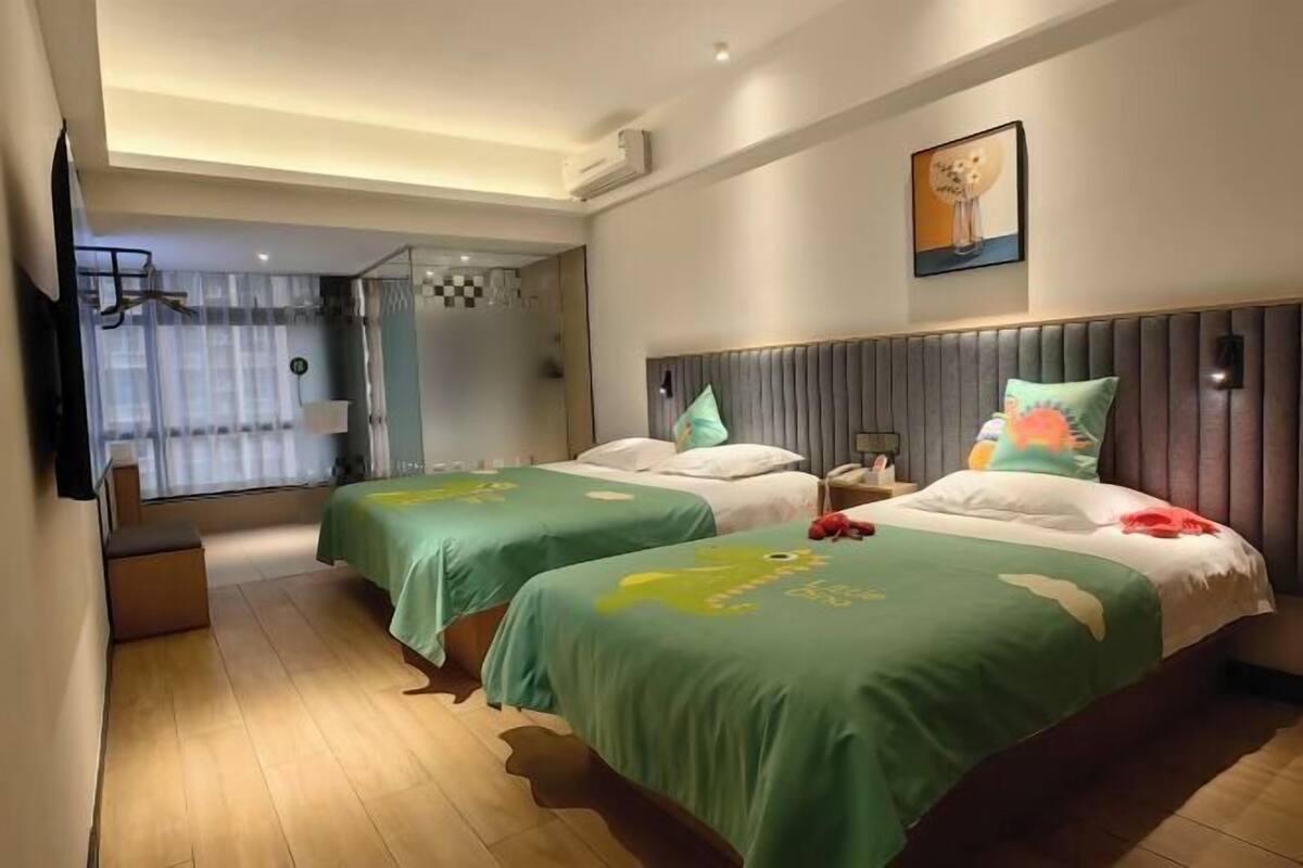 Una habitación de hotel con dos camas, un ventanal grande, un televisor de pantalla plana y un cuadro en la pared.