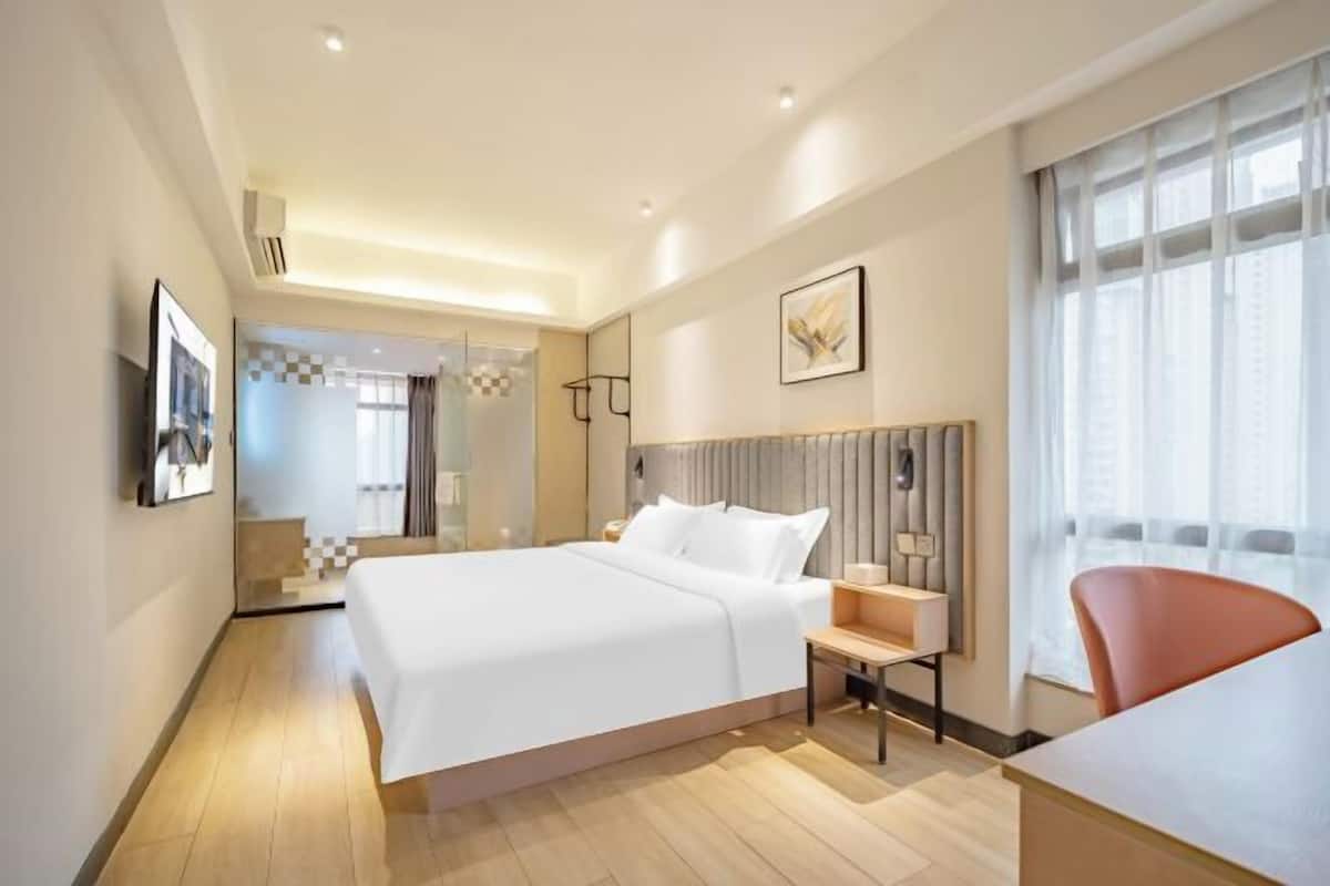 Una habitación de hotel moderna con una cama grande, una mesita de noche y una silla.