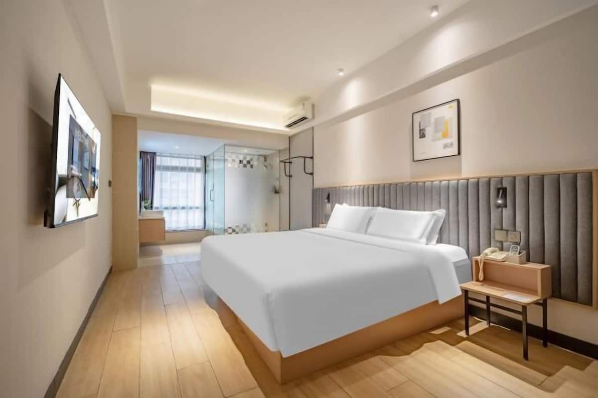 Habitación de hotel moderna con una cama grande, mesita de noche y vistas al exterior.