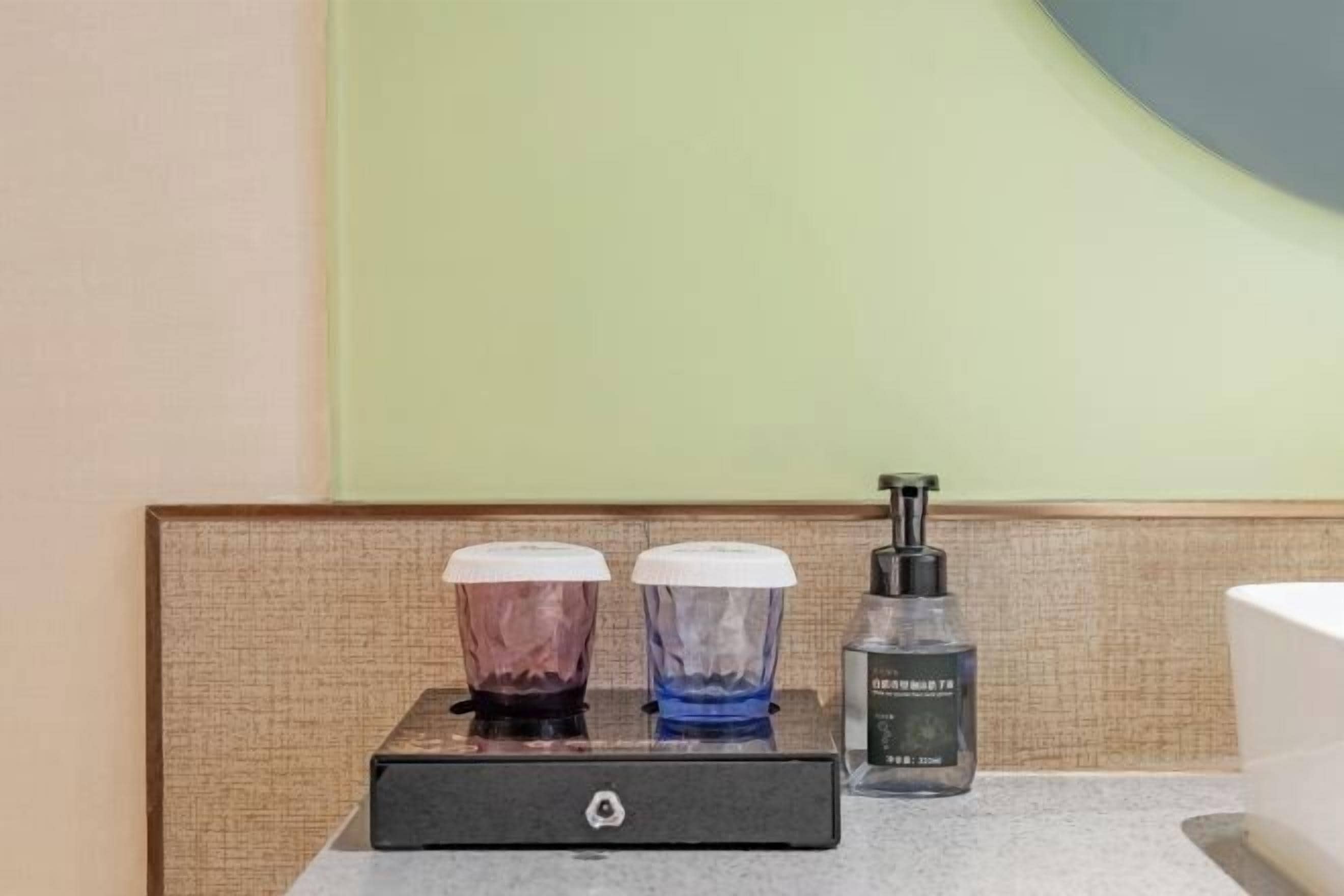 A bathroom with a countertop, two soap dispensers, and a bottle of hand sanitizer.