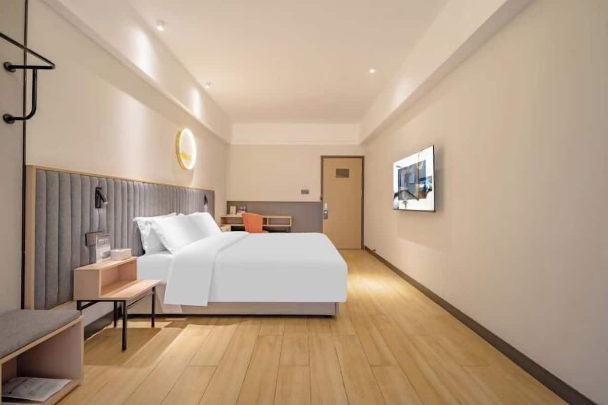 Una habitación de hotel moderna con una cama grande, mesitas de noche, un escritorio y una silla.