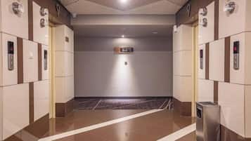 A modern elevator area with a digital display, a trash bin, and a tiled floor.