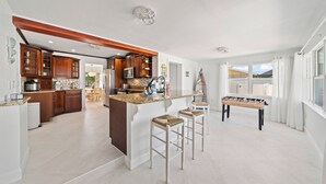 A spacious kitchen with wooden cabinets, a granite countertop, and a foosball table. - Villa Paradisus. Heated Pool! 6 min to the beach (Satellite Beach)