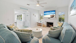 A living room with a TV, a fireplace, and a ceiling fan. - Villa Paradisus. Heated Pool! 6 min to the beach (Satellite Beach)