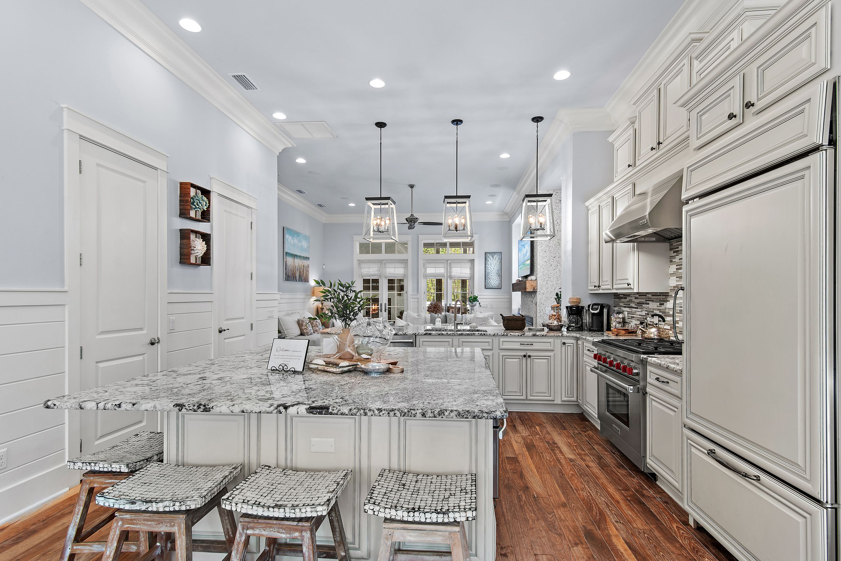 A spacious kitchen with a large island, white cabinetry, and a wooden floor.