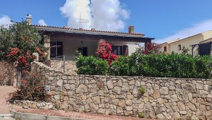 A stone-walled building with a tiled roof, a stone staircase, and red flowering plants. - Villa da Anna e Turi - 5 minutes from the beach (San Gavino ( frazione di Budoni))