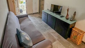 A living room with a brown sofa, a TV on a cabinet, and framed fish pictures on the wall. - Villa da Anna e Turi - 5 minutes from the beach (San Gavino ( frazione di Budoni))