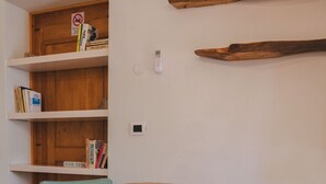 Una habitación con una mesa de madera, dos sillas, una estantería y una planta pequeña.