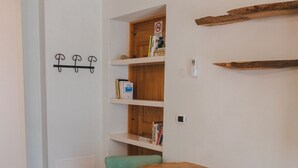 Un comedor con una mesa de madera y dos sillas, una estantería y un perchero.