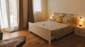 Un dormitorio con cama, mesitas de noche y una ventana con cortinas.