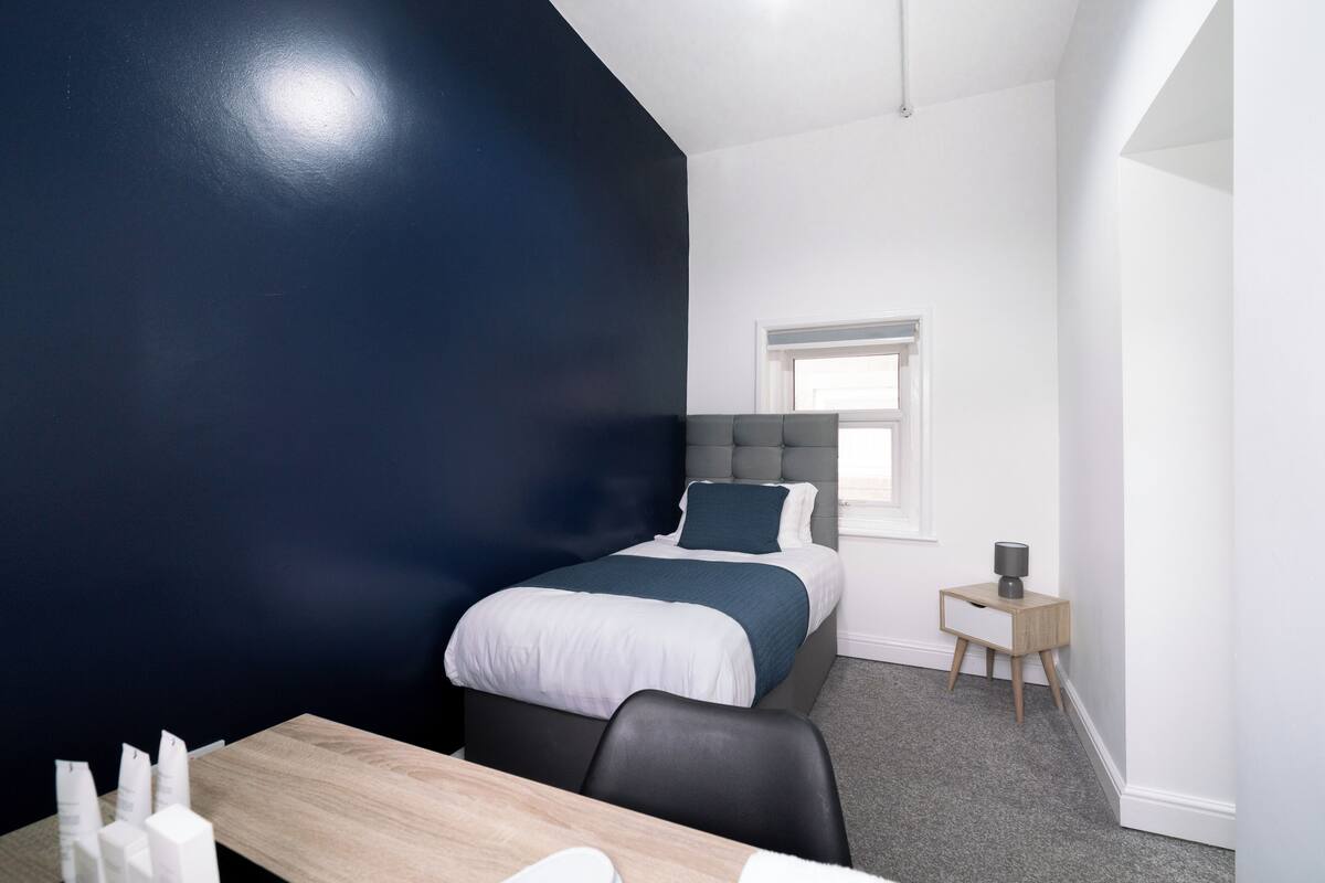 Une chambre à coucher moderne avec un grand lit, une table de chevet et une fenêtre.