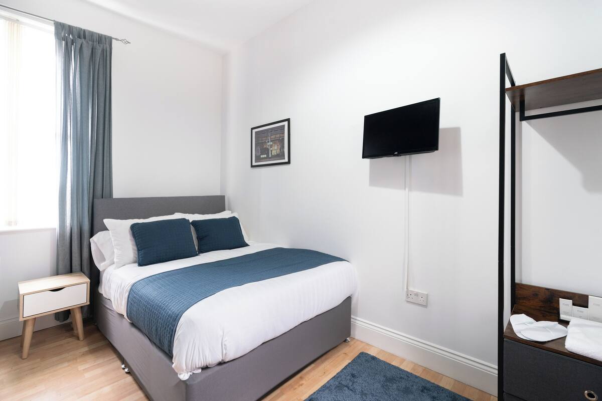 Une chambre à coucher moderne avec un lit, une table de chevet, une télévision et un miroir.