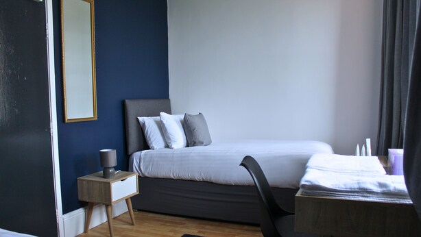 Une chambre à coucher comprenant un lit, une table de chevet, une chaise et une petite table avec une lampe.