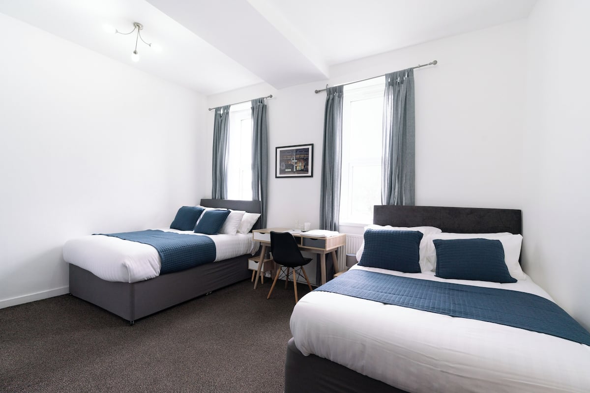 Une chambre d’hôtel avec deux lits, un bureau et une chaise.