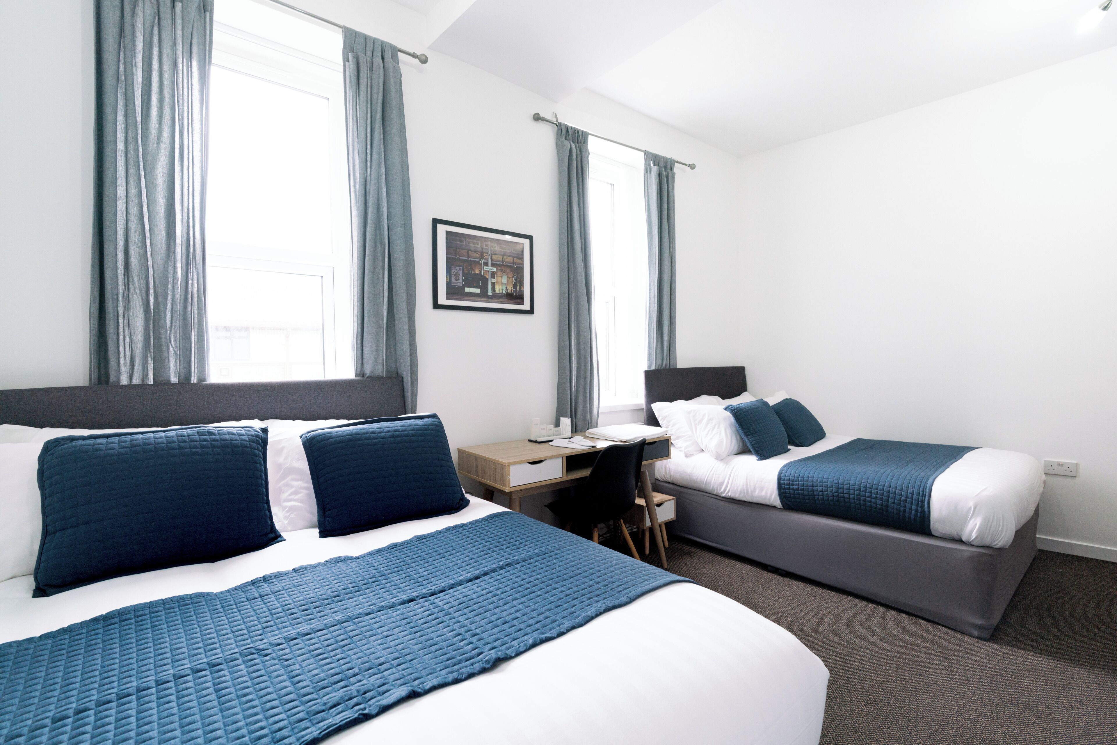 A hotel room with two beds, a desk, and a chair.