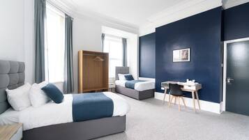 Una habitación de hotel moderna con dos camas, un escritorio y un armario.