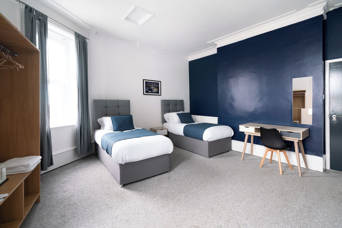 Une chambre d’hôtel moderne avec deux lits, un bureau et une chaise.