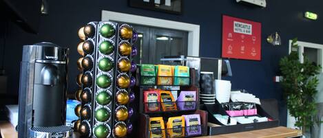 A coffee station with a coffee machine, a display of coffee pods, and a sign for Newcastle Hotel & Bar.