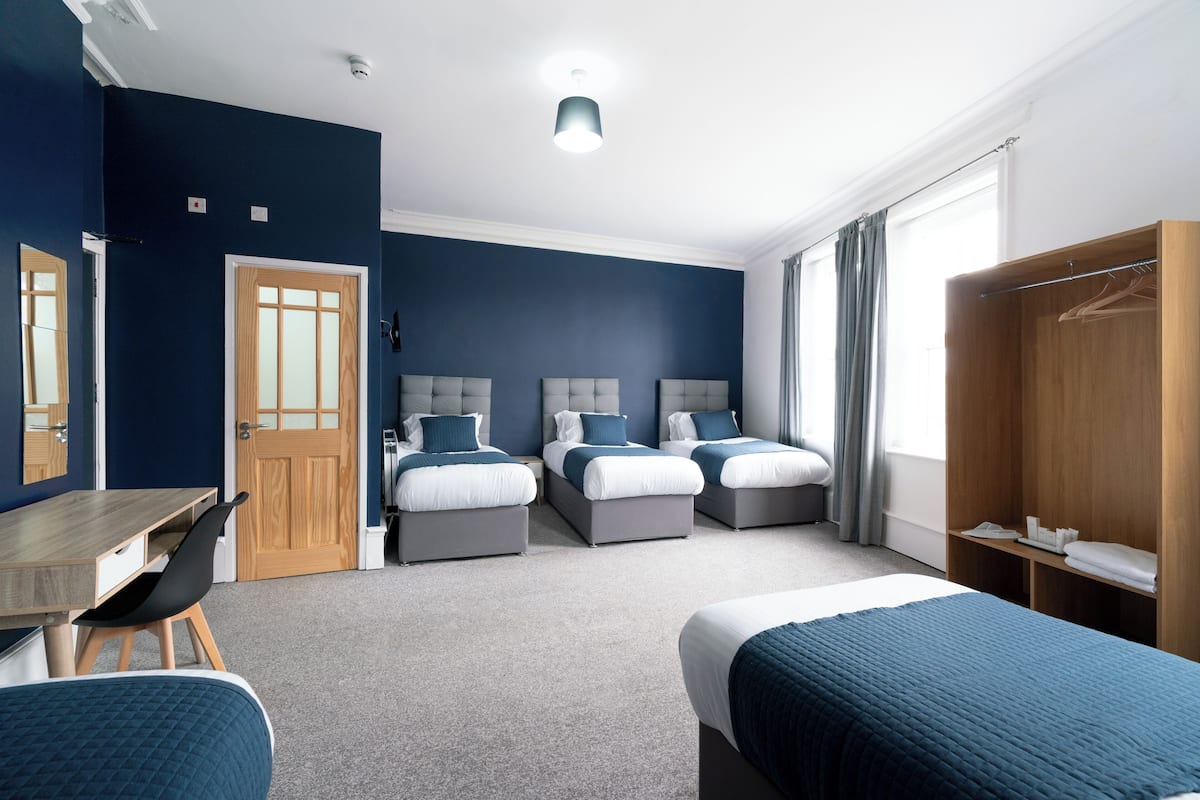 Une chambre d’hôtel avec deux lits, un bureau et une armoire.