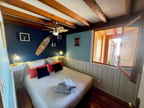 A bedroom with a bed, a ceiling fan, a window, and wall decorations.