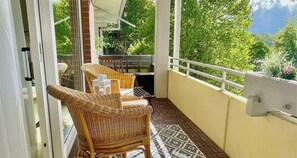Un balcon avec des fauteuils en osier, une petite table et un sol à motifs.