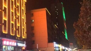 A nighttime urban scene with illuminated buildings and a prominent green vertical light on a skyscraper. - Kuqa Haodu Business Hotel (Kuqa)