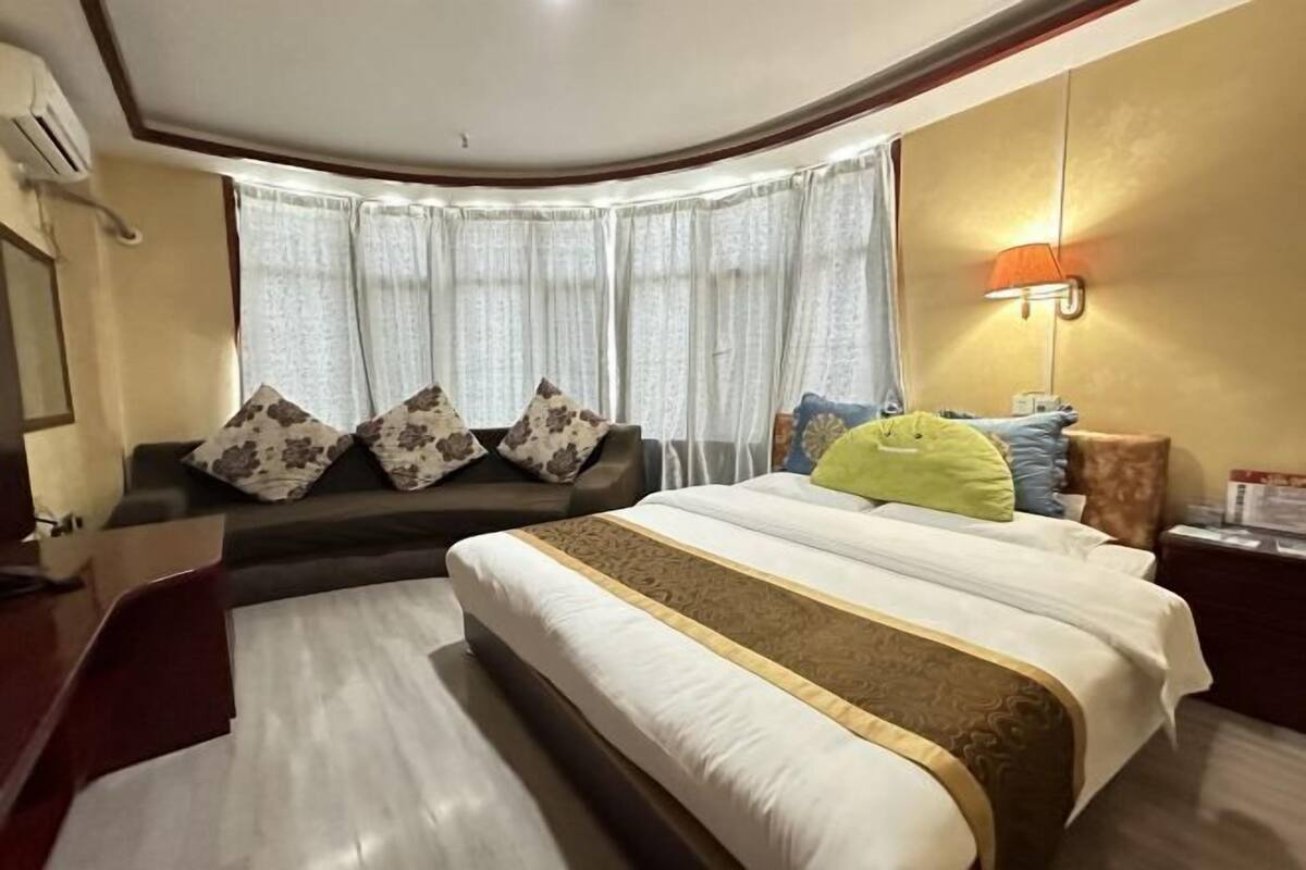 A hotel room with a bed, a sofa, a desk, and a lamp.