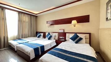 A hotel room with two beds, a nightstand, a lamp, and a painting on the wall.
